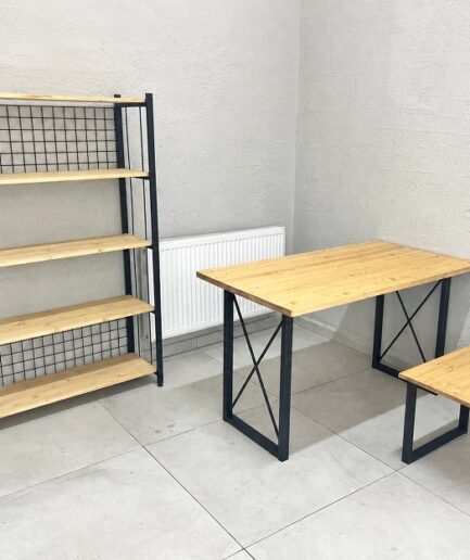 Wooden desk and matching bench with black metal frames in a minimalist home office setup, next to a tall wooden shelf unit with grid backing.