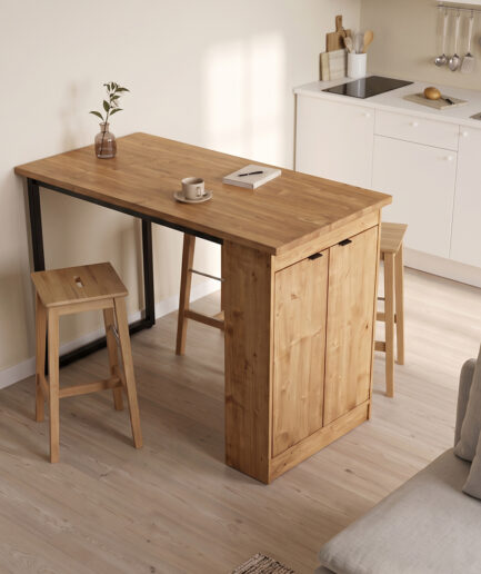 Wooden kitchen island with storage, two stools, a mug and notebook on top, and a small plant in a glass vase.