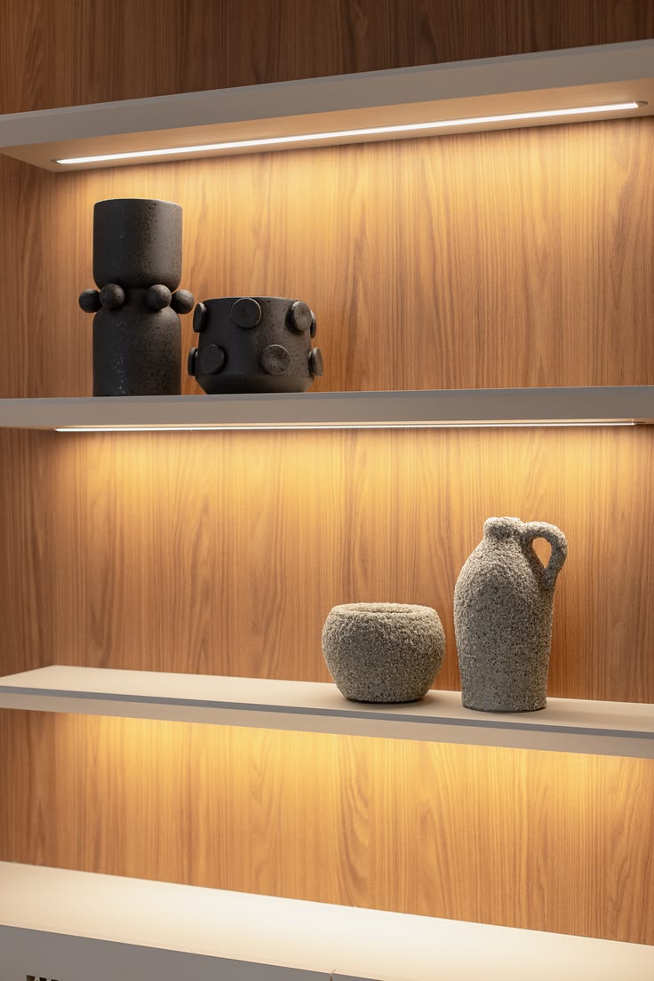 raf-alti-led Textured gray ceramic pitcher and small bowl on a white shelf against warm wood paneling with backlighting